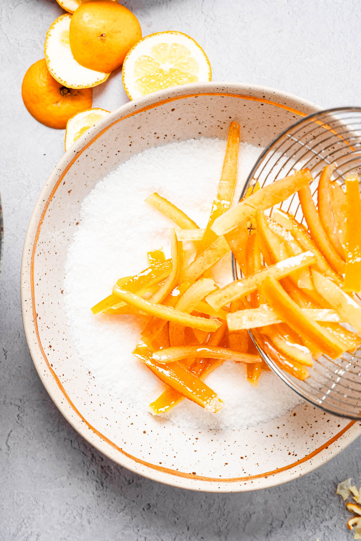Candied orange peels being added to a bowl of fine granulated sugar fro coating