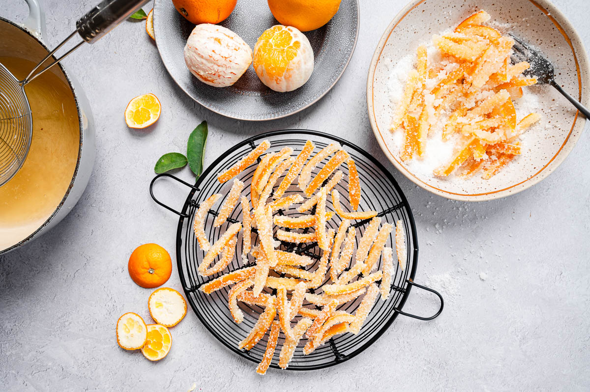 Candied orange peels coated in sugar and drying on a cooling rack