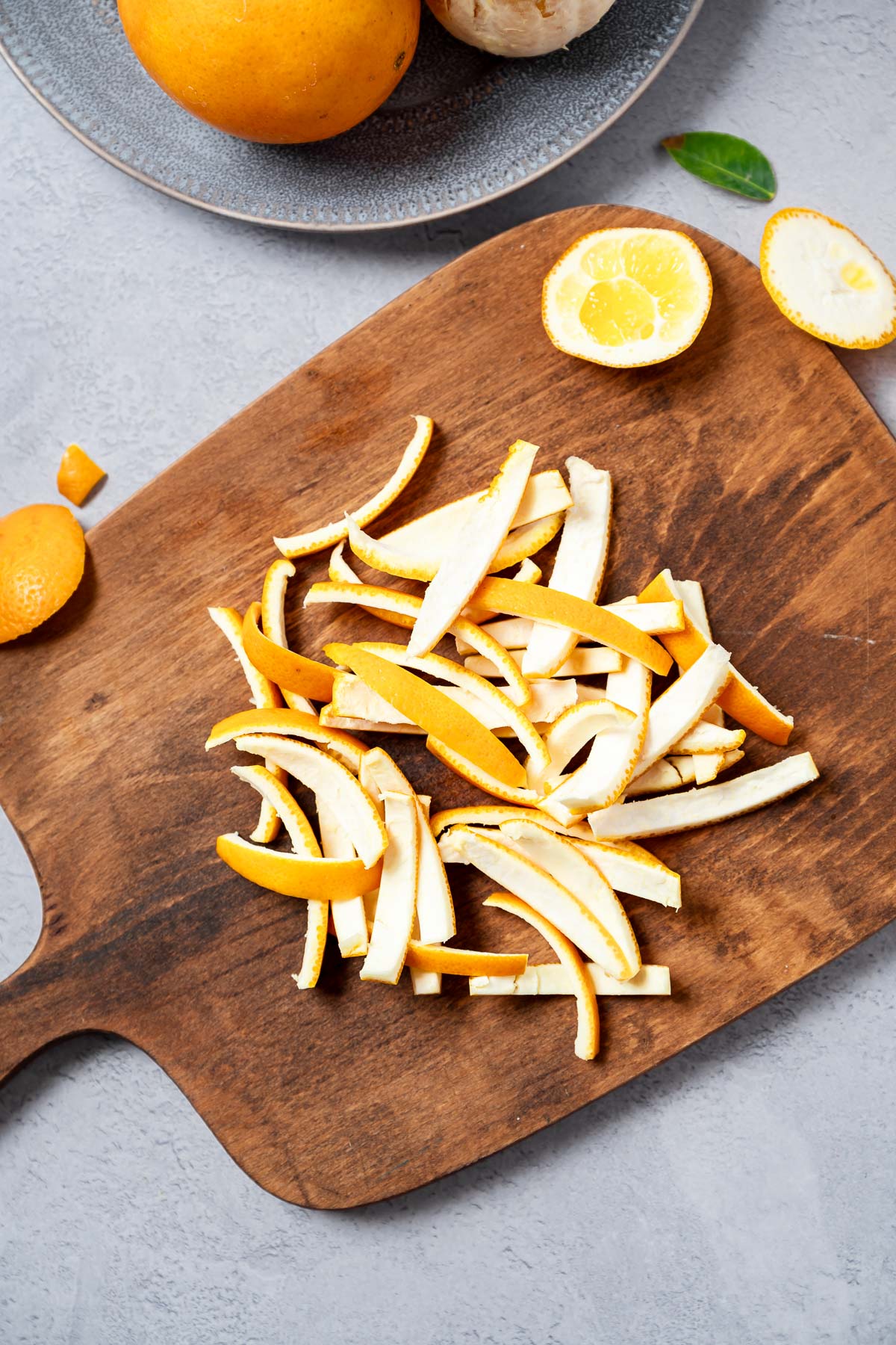 Freshly sliced orange peels in a pile on a wooden cutting board