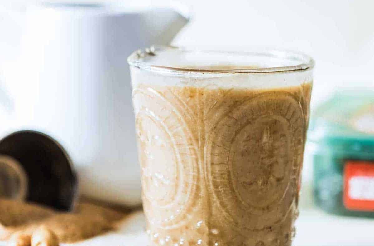 Healthy caramel protein shake in an etched glass next to pitted dates