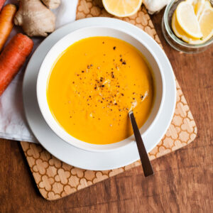 Carrot ginger soup recipe in a white bowl with cracked black pepper.