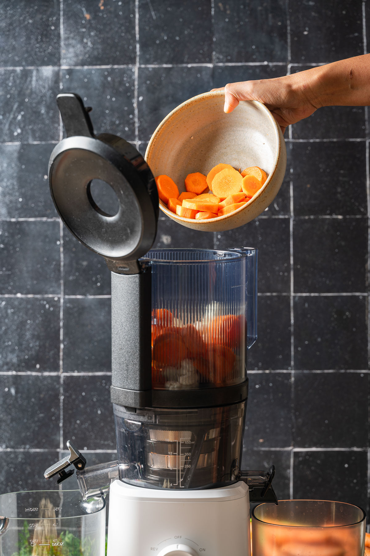 A person adding sliced carrots in the juicer