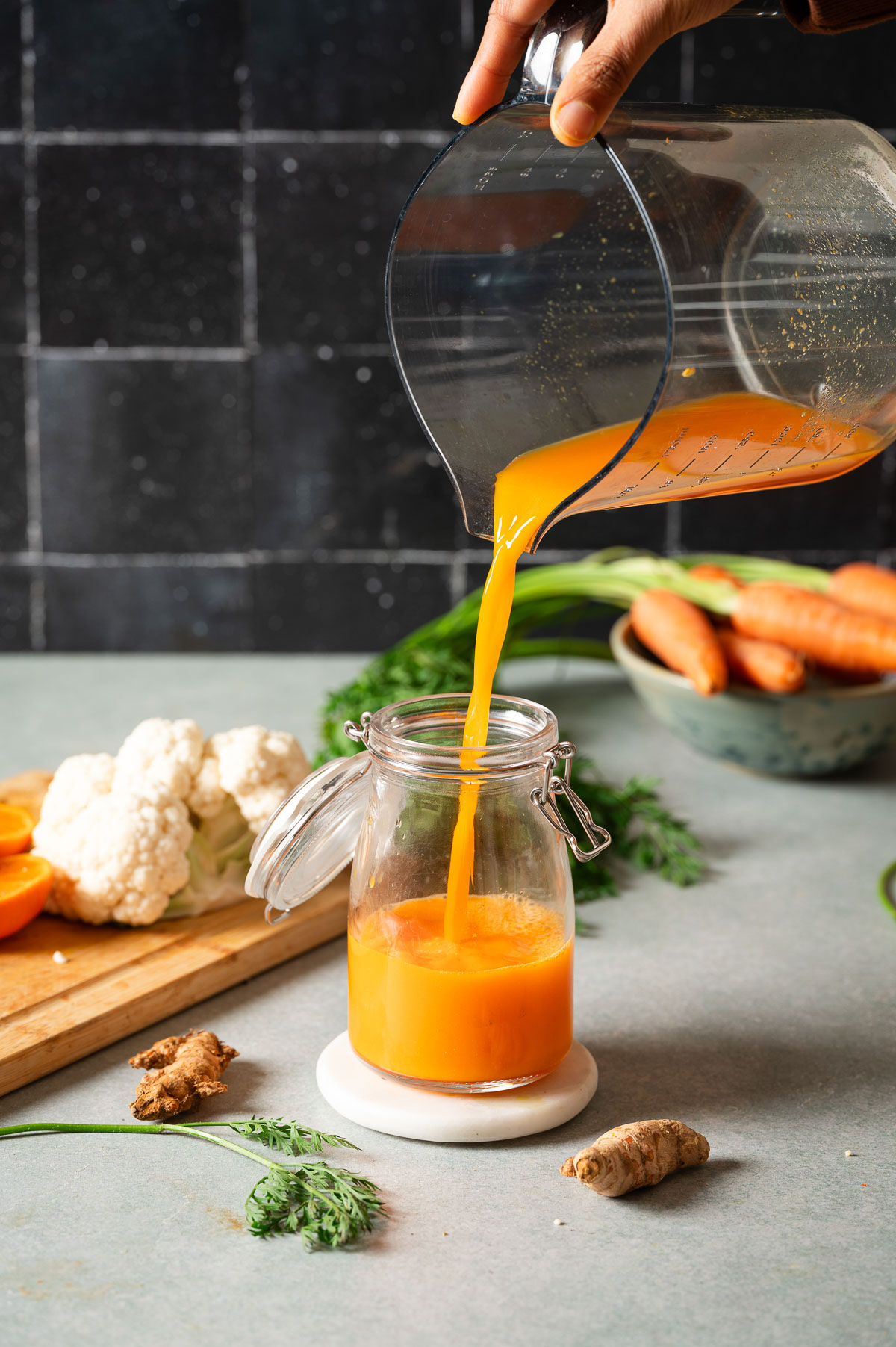 Pouring carrot turmeric juice in a glass jar
