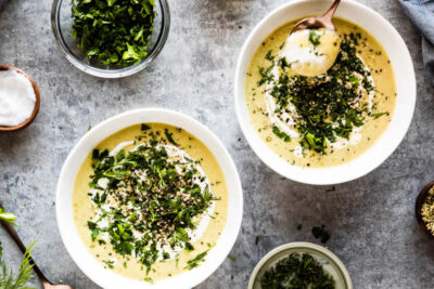 Celery soup with fresh herbs chopped on top with swirl of cashew cream.
