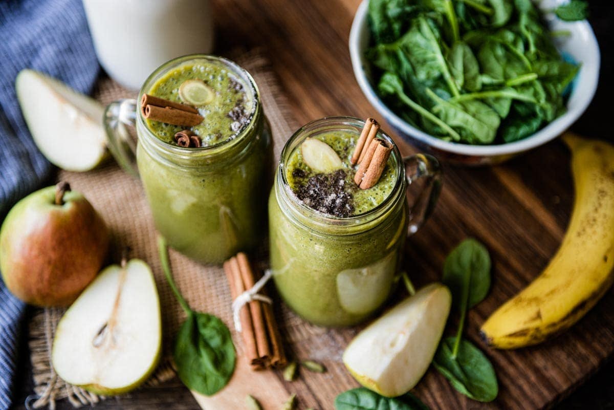 Mugs of chai smoothies surrounded by ingredients.