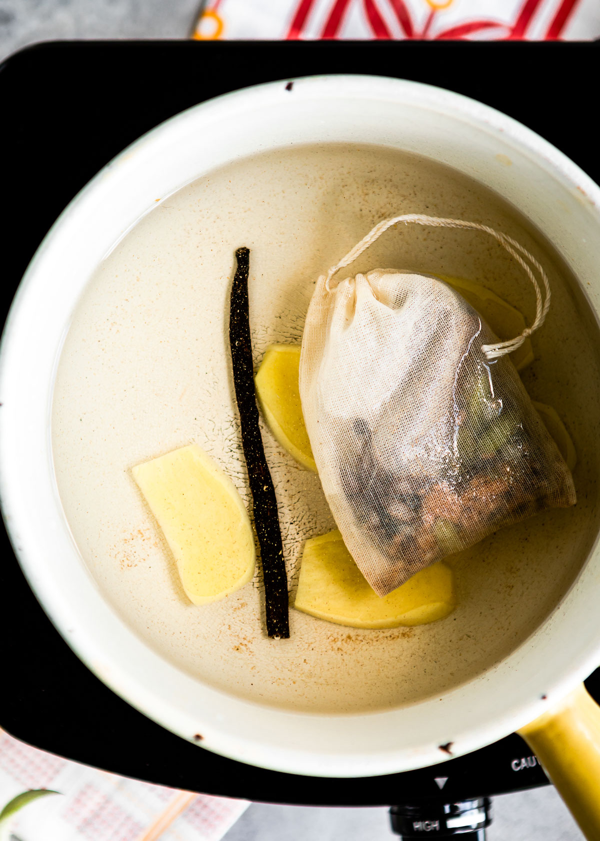 Whole spices boiling in water inside a stainless steel saucepan