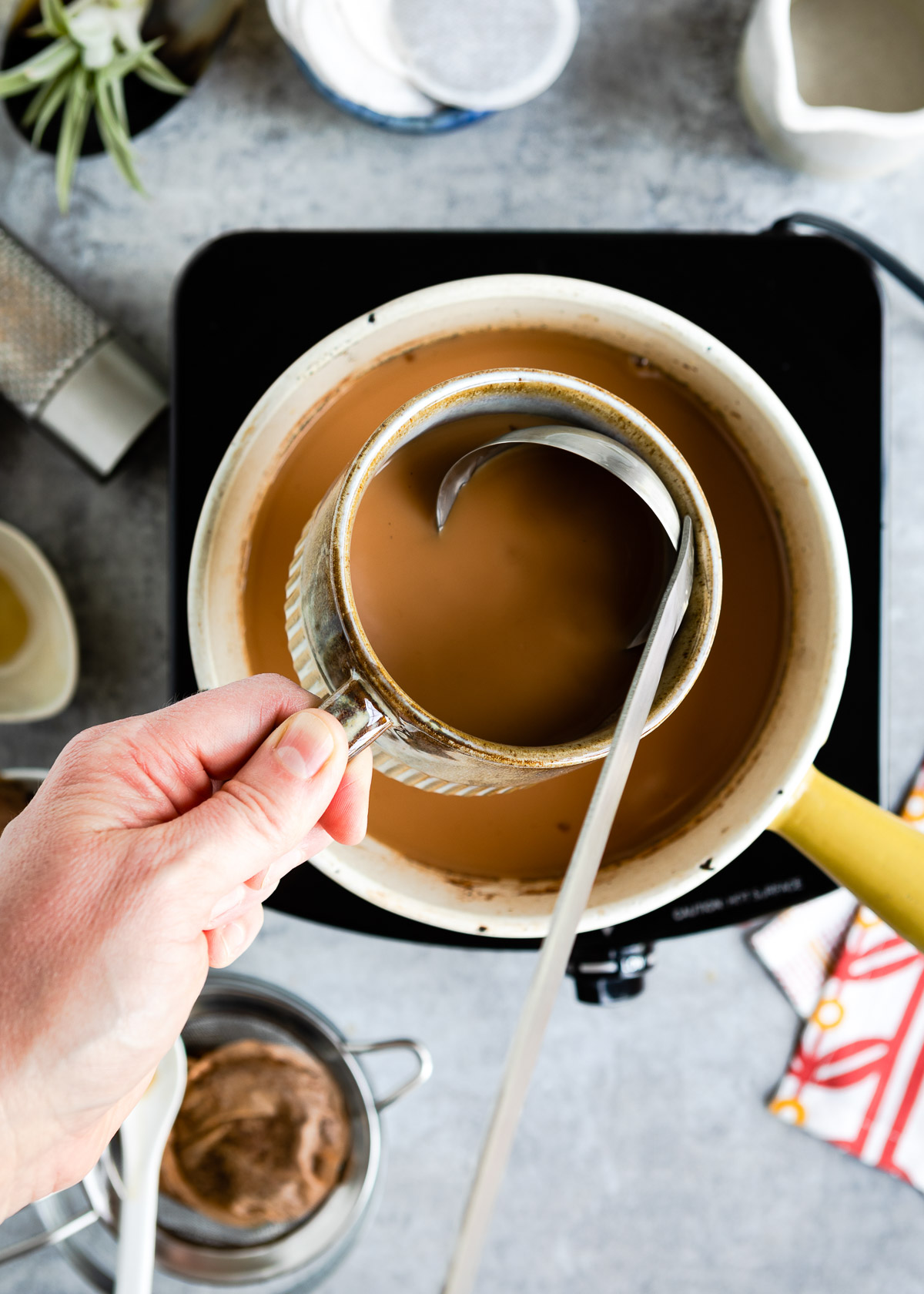 A person pouring chai latte with a ladle