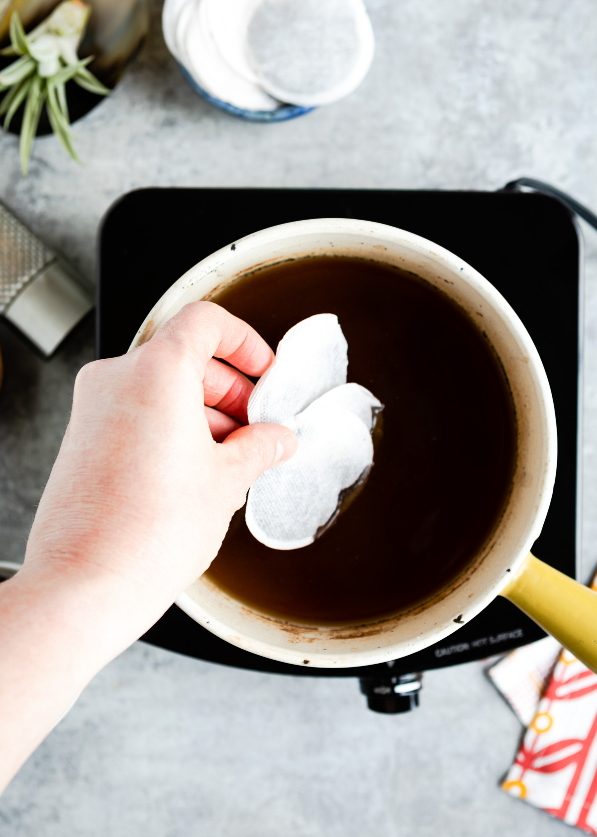 A person adding two tea bags in a chai base