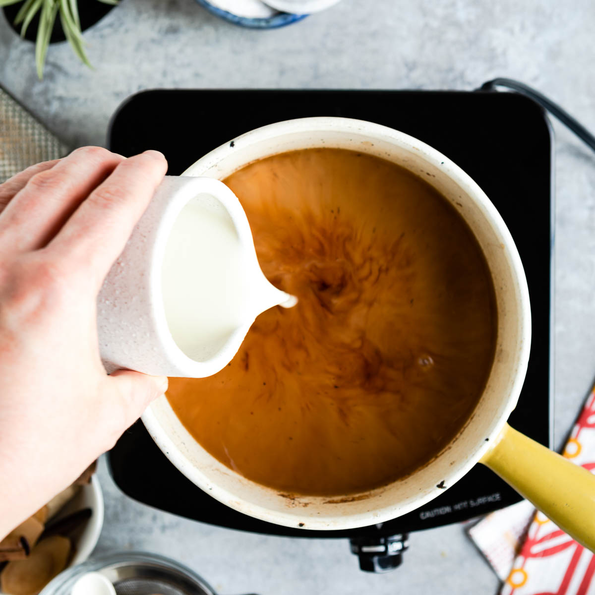 Adding oat milk to a spiced water and tea mix