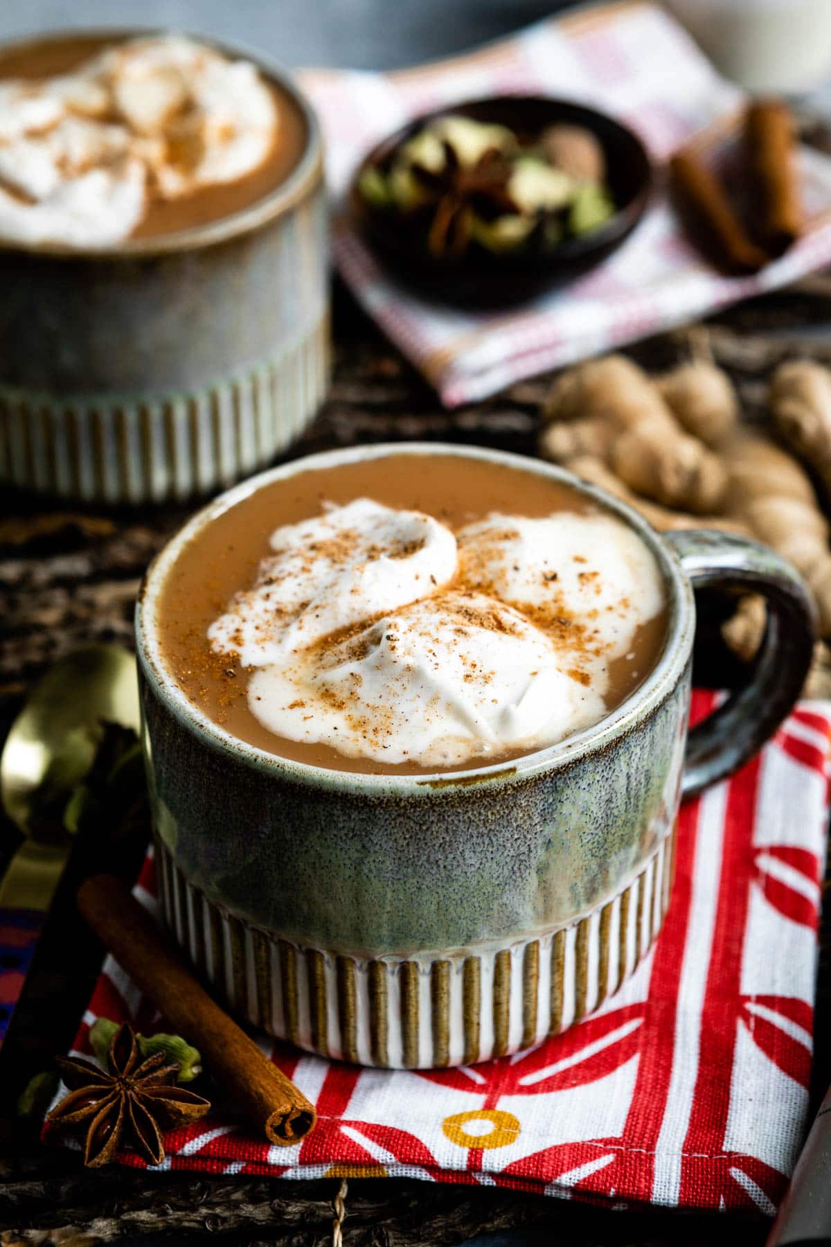 close up photo of chai tea latte topped with spices and coconut whipped cream