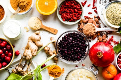 Assorted fresh fruits, berries, and superfoods for smoothies on a white surface.