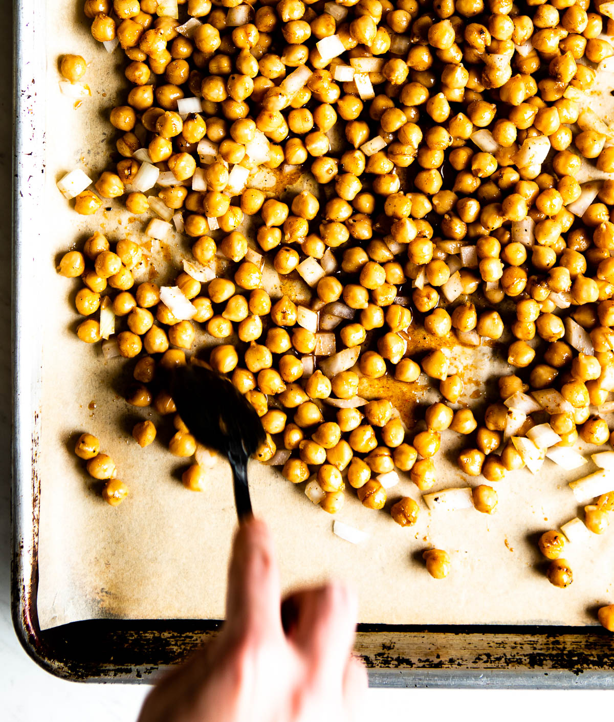 baking sheet with parchment paper and seasoned chickpeas ready to be baked