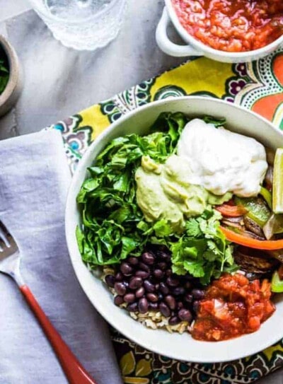 chipotle veggie bowl in a white bowl on a tea towel next to a cloth napkin and fork.