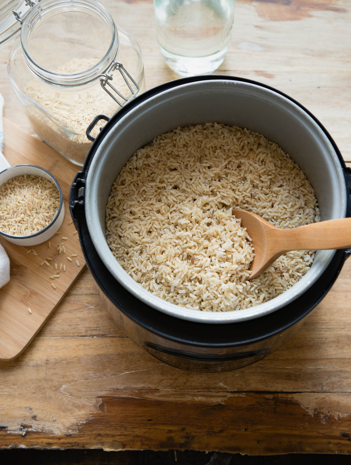 A steaming pot of freshly cooked brown rice with a wooden spoon.