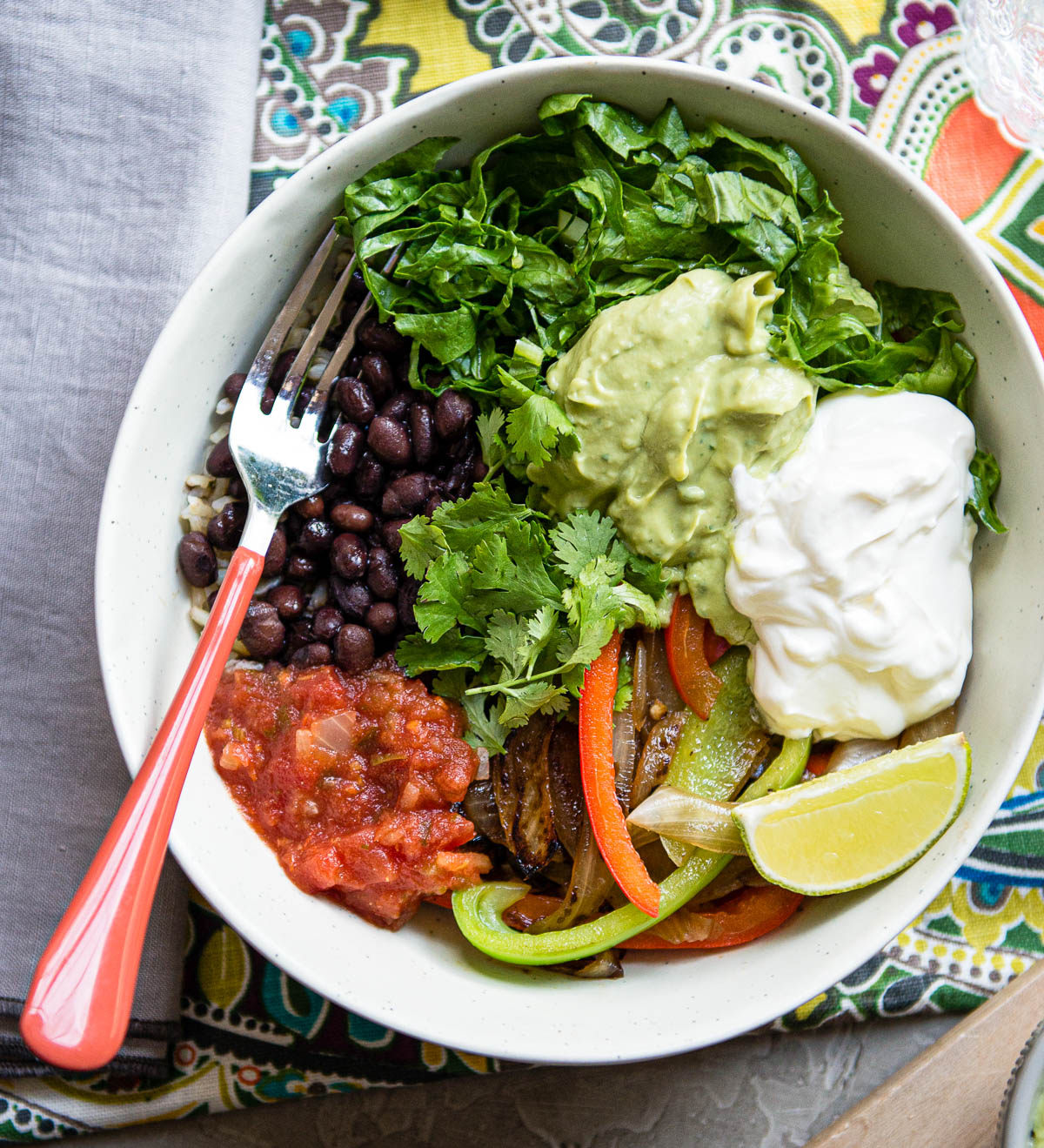 A fork in a heathy and colorful chipotle veggie bowl ready to eat.