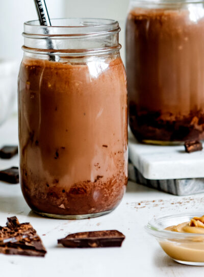 Chocolate peanut butter smoothie in two jars with straws.