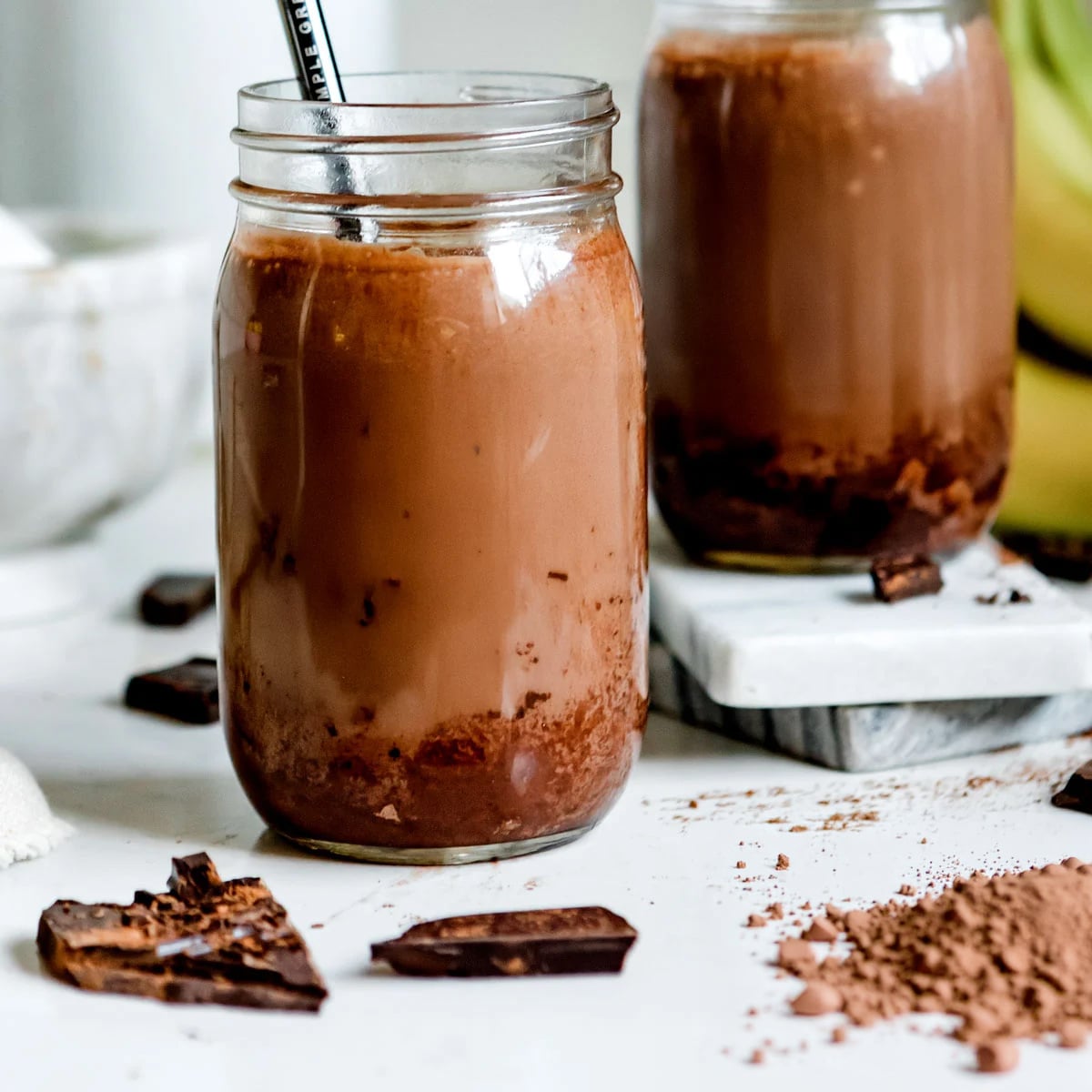 Chocolate peanut butter smoothie in two jars with straws.