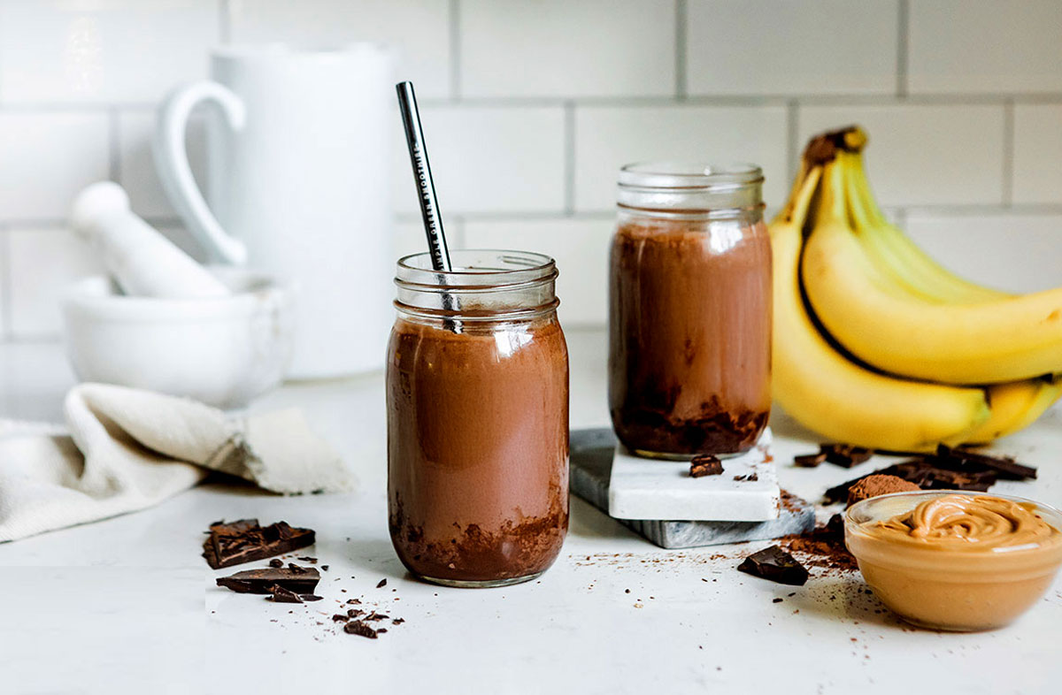 Kitchen counter with chocolate peanut butter smoothies in mason jars.