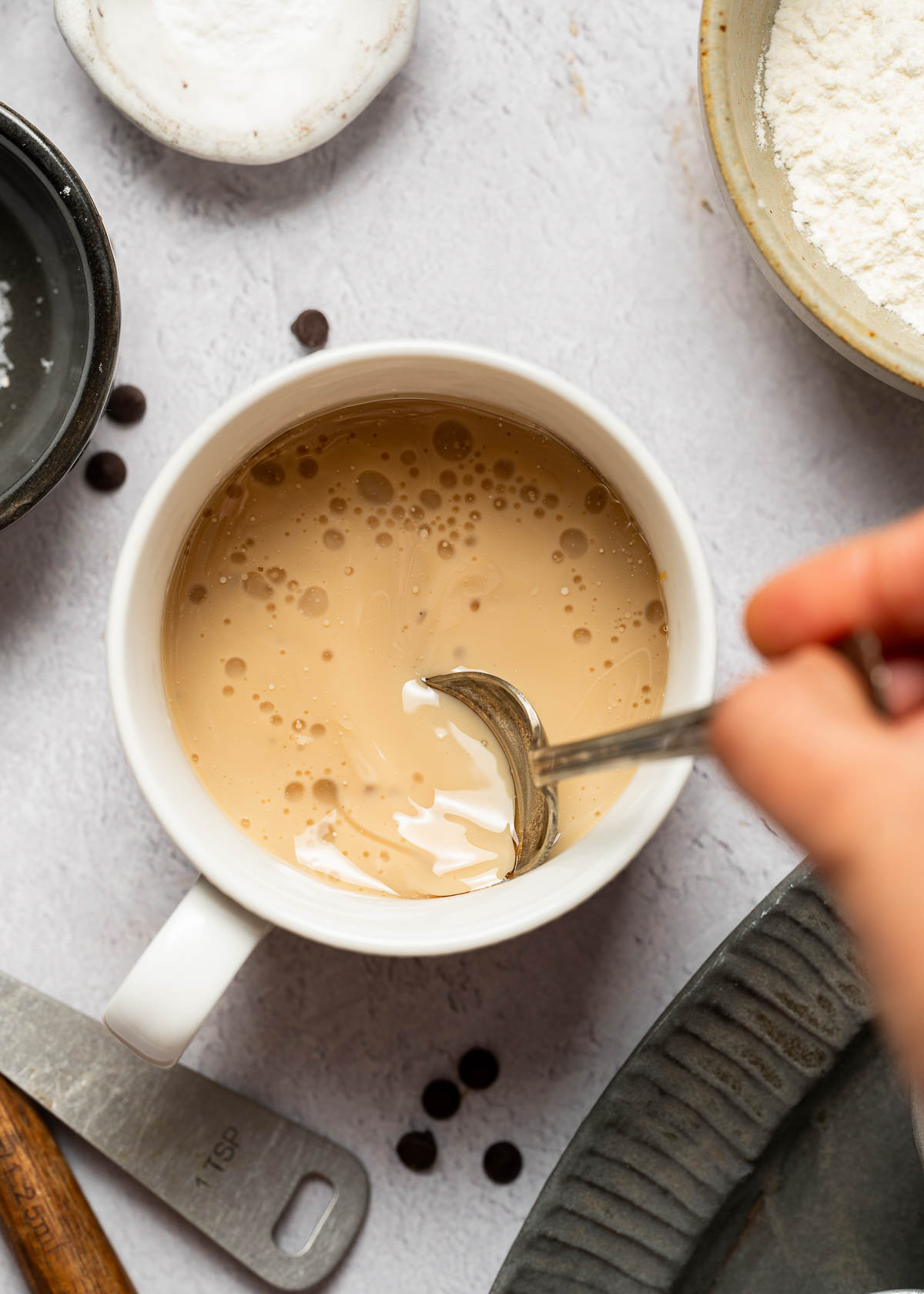 Wet ingredients being stirred into a vegan chocolate mug cake. 