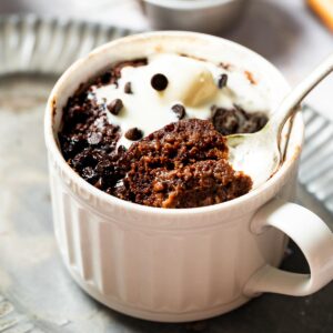 A vegan chocolate mug cake topped with dairy free ice cream.