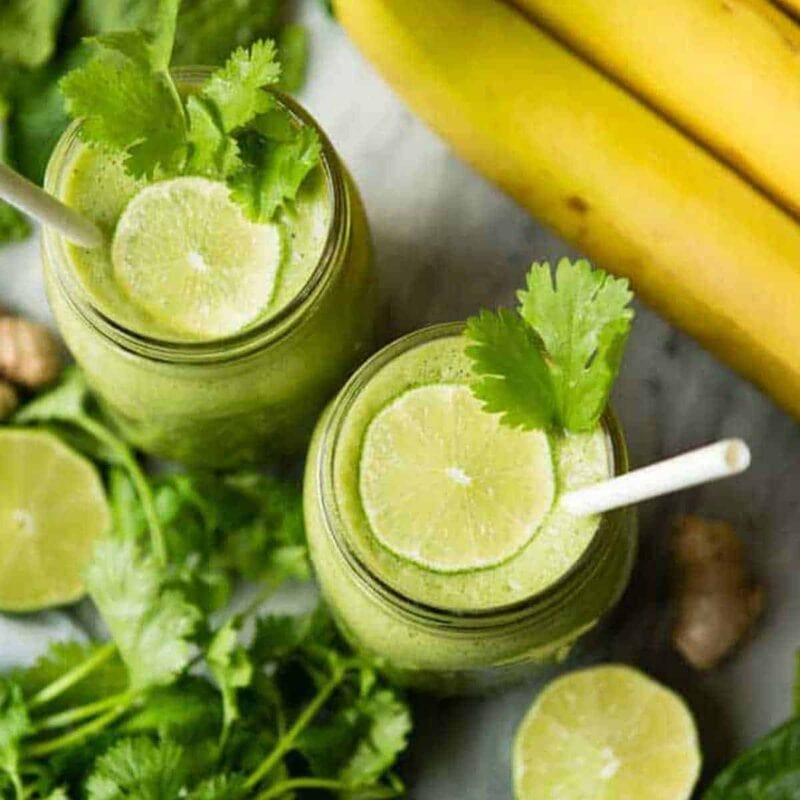 Two cilantro smoothie topped with lime slices.