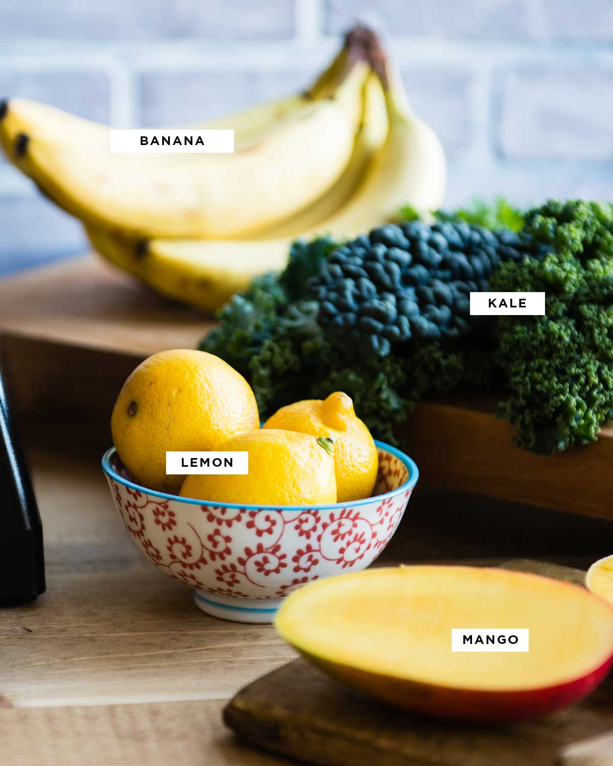ingredients for a citrus smoothie recipe including bananas, kale, lemons and mango