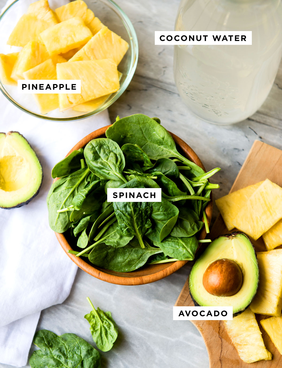 labeled ingredients for a clear skin smoothie including coconut water, pineapple, spinach and avocado.