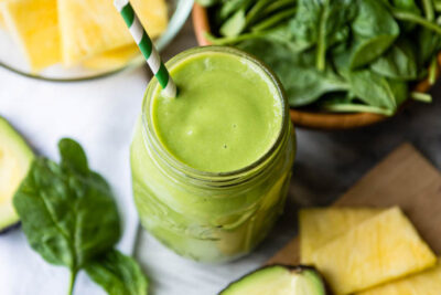 Green smoothie on table with straw.