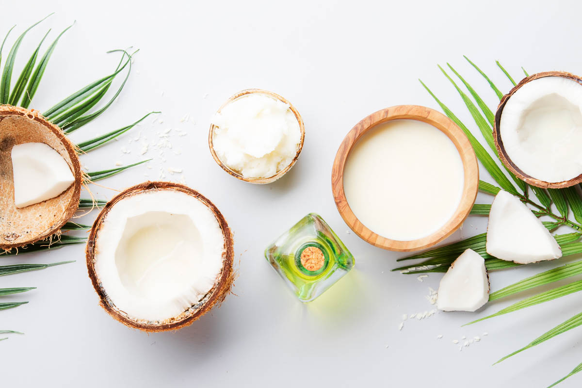 showing uses of coconut oil in an oil, a container of lotion, and a bowl of solid coconut oil.