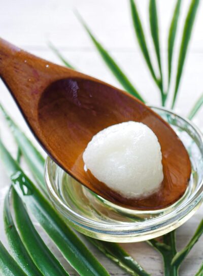 a wooden spoon with solid coconut oil sitting in it.
