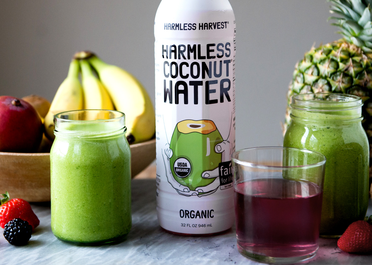Store-bought coconut water next to smoothie and bowl of fruit