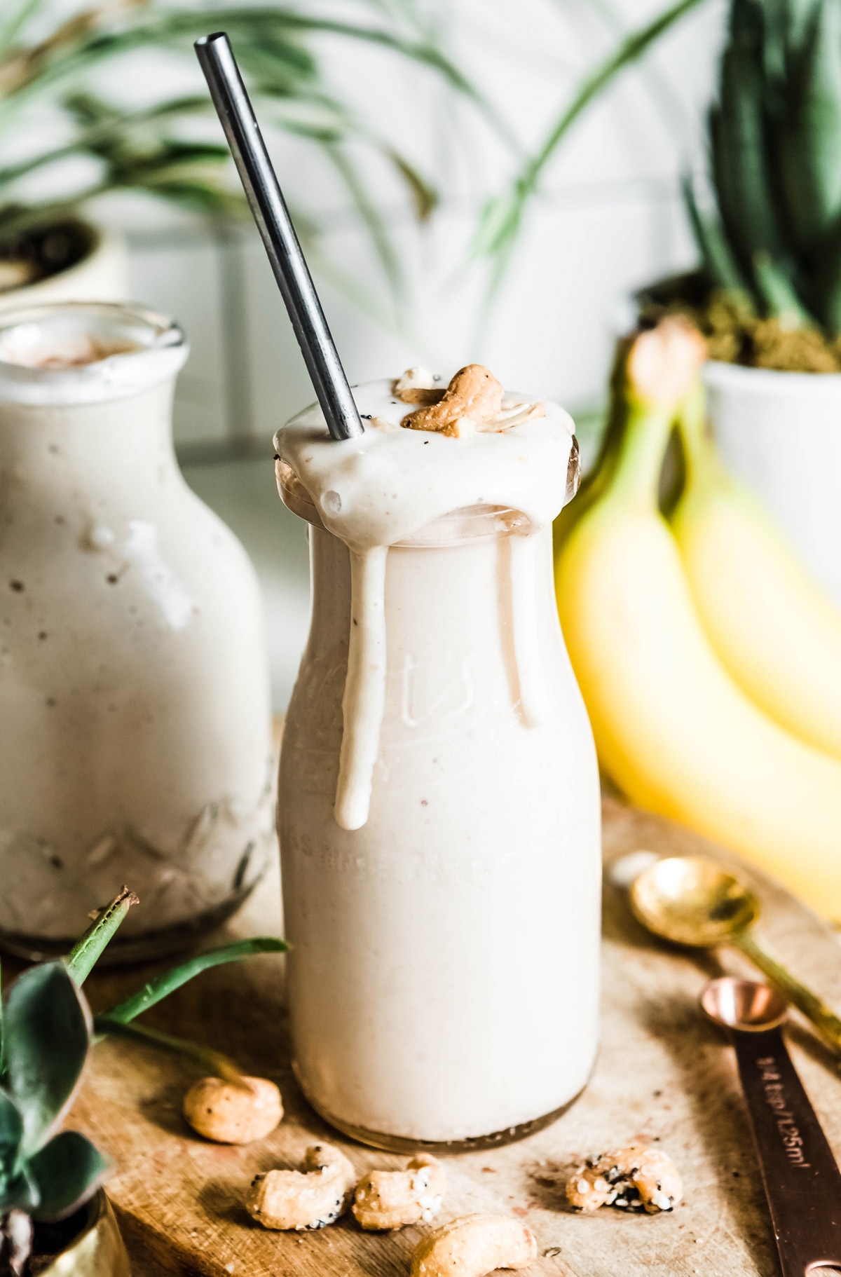 Glass of banana smoothie with straw and fresh bananas on table