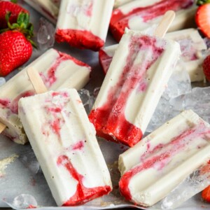 creamy strawberry popsicles in a pile over ice.