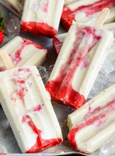 creamy strawberry popsicles in a pile over ice.