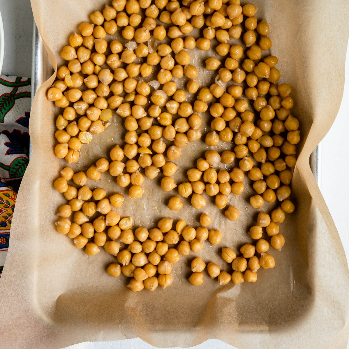 Garbanzo beans on a parchment lined baking dish.