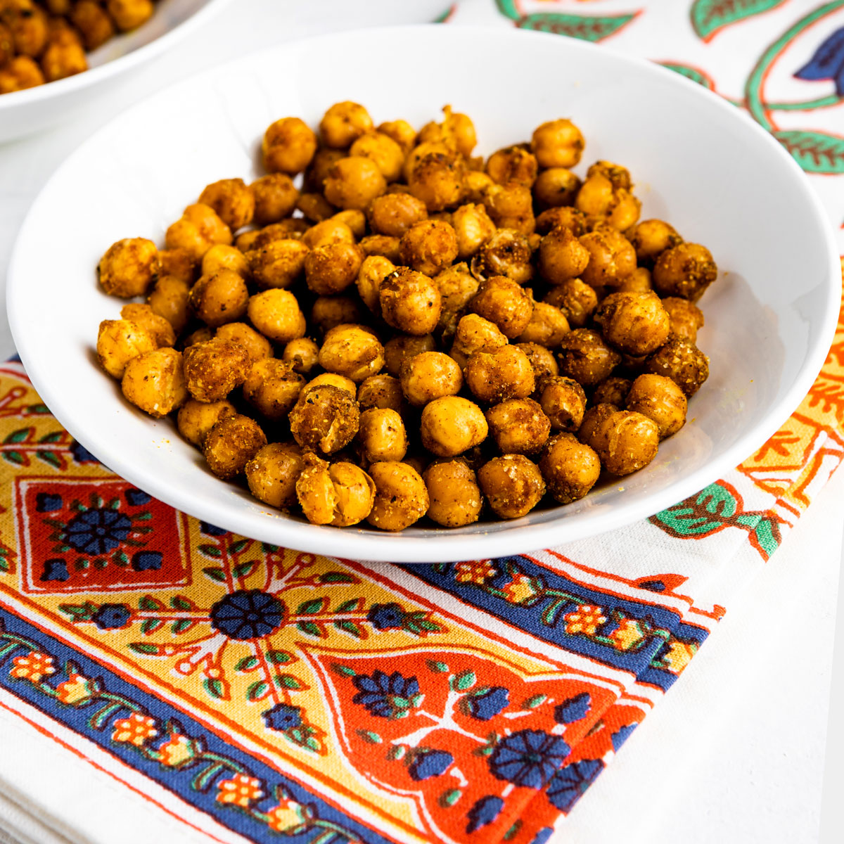 Curry roasted chickpeas in a serving bowl on a white table.