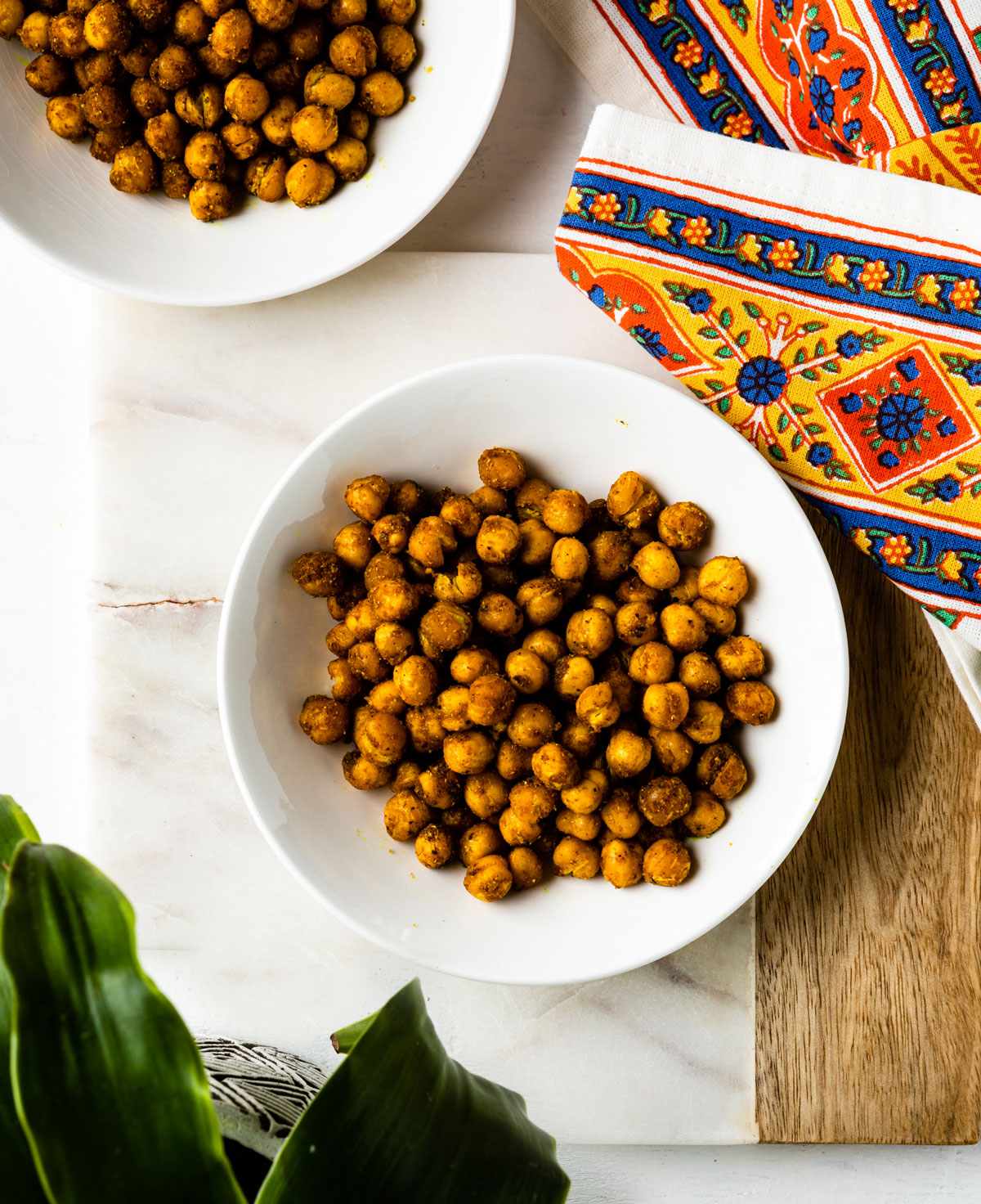 Table with bowl of roasted chickpeas with an ornate, indian-style napkin.