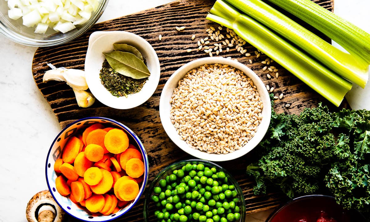 overhead photo of food you can eat on the Daniel Fast Meal Plan including celery, carrots, peas, kale, spices, onions, mushrooms and brown rice.