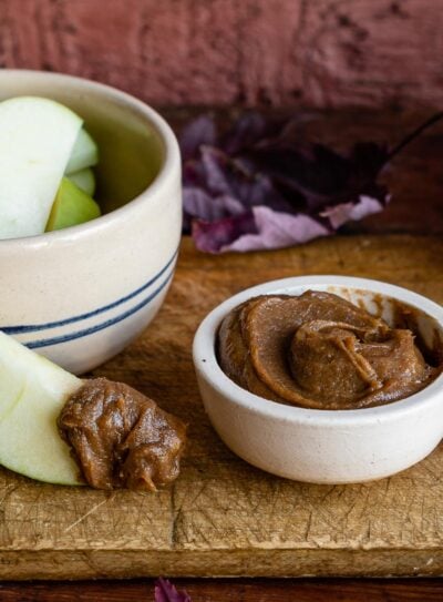 Small bowl of creamy date caramel recipe with a fresh apple slice dipped