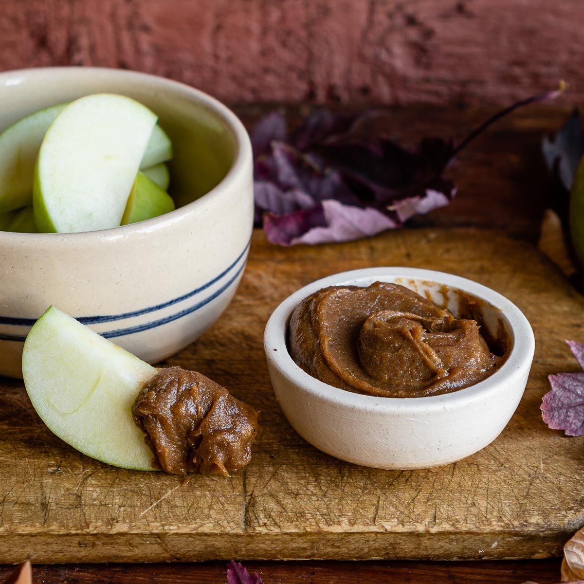 Small bowl of creamy date caramel recipe with a fresh apple slice dipped
