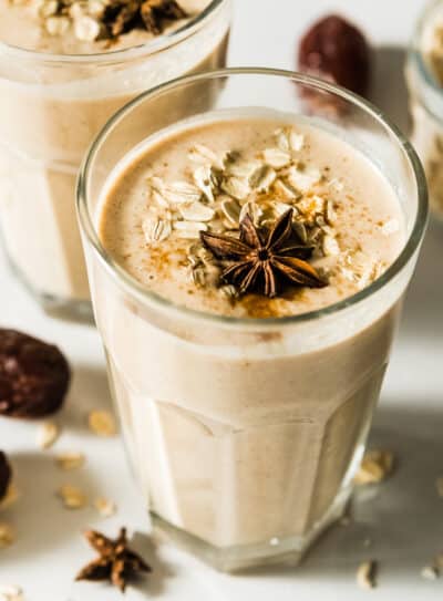 Creamy cinnamon date smoothie topped with oats and star anise in a glass.