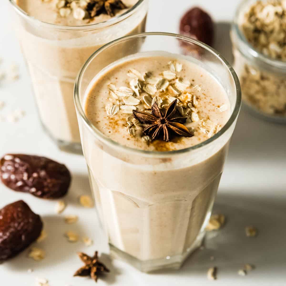 Creamy cinnamon date smoothie topped with oats and star anise in a glass.