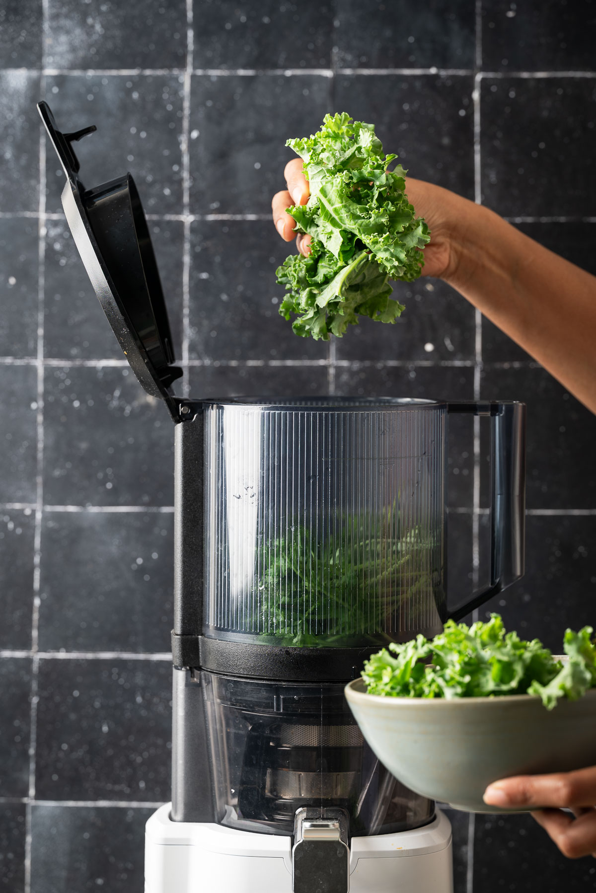 A person adding kale in a juicer