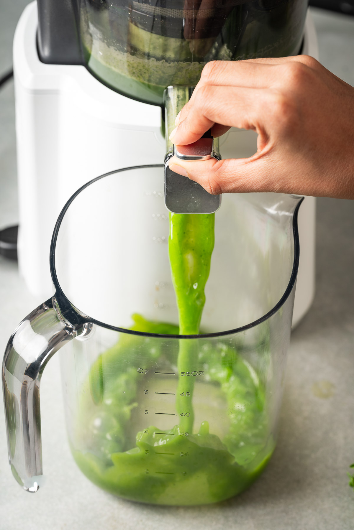 A person pouring green juice from a juicer
