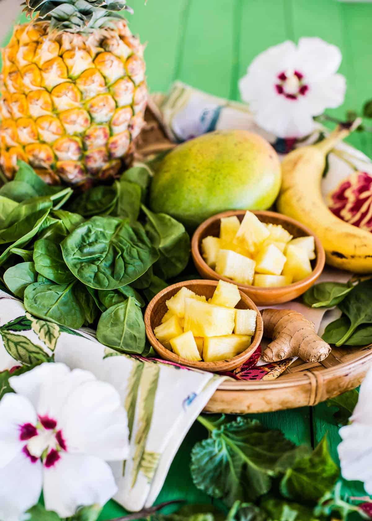 Fresh tropical fruits including pineapple, mango, banana, and pineapple on a green background.