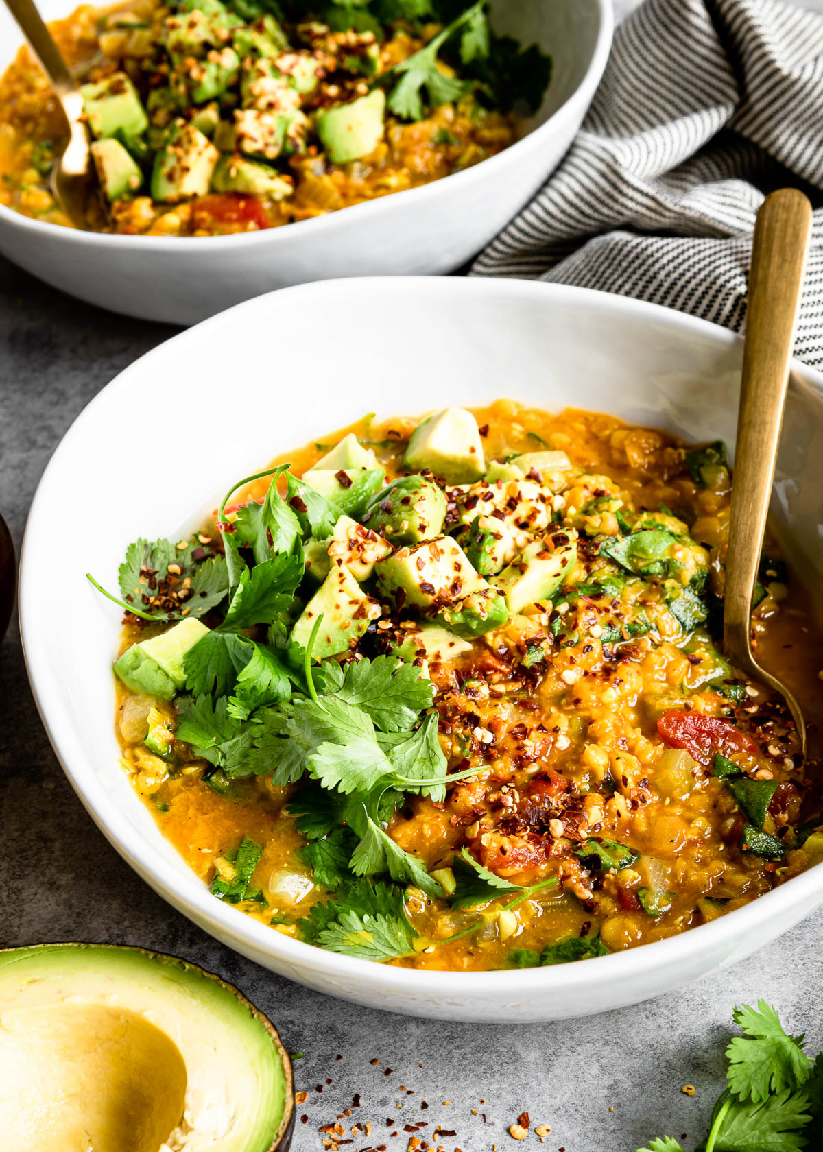 a bowl of yellow lentils topped with avocado and cilantro.