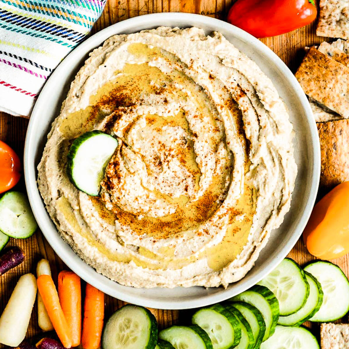 snack recipe of a homemade hummus surrounded by fresh veggies.