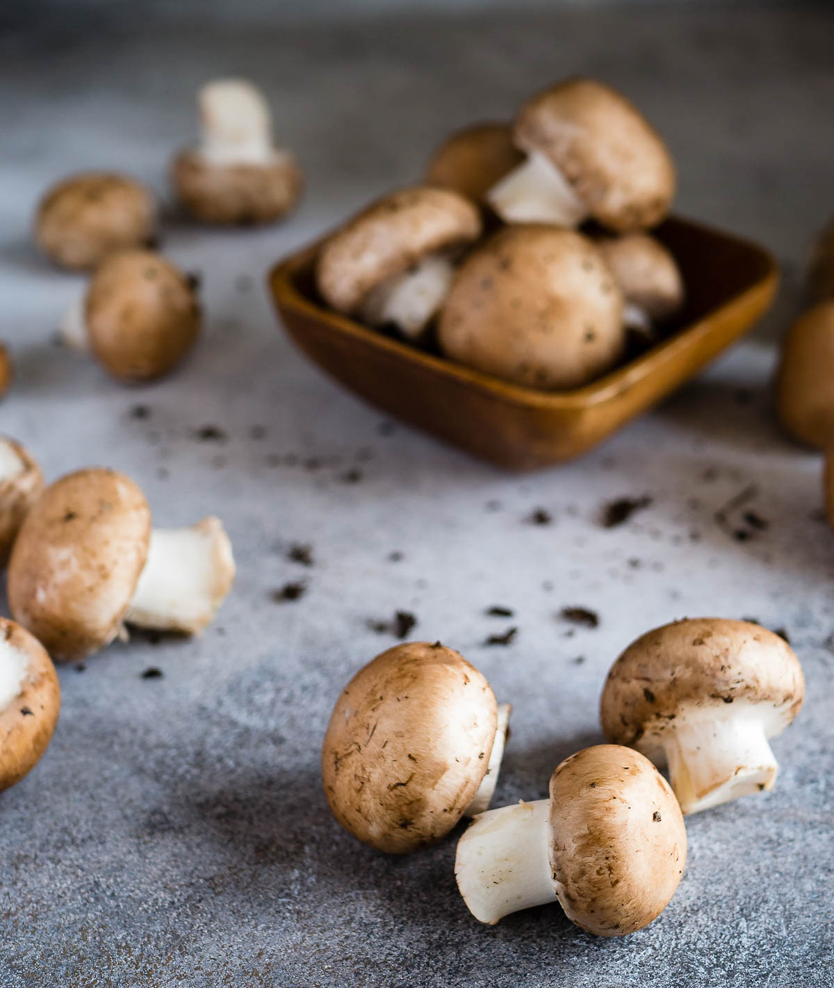 several button mushrooms sitting on a stone countertop.