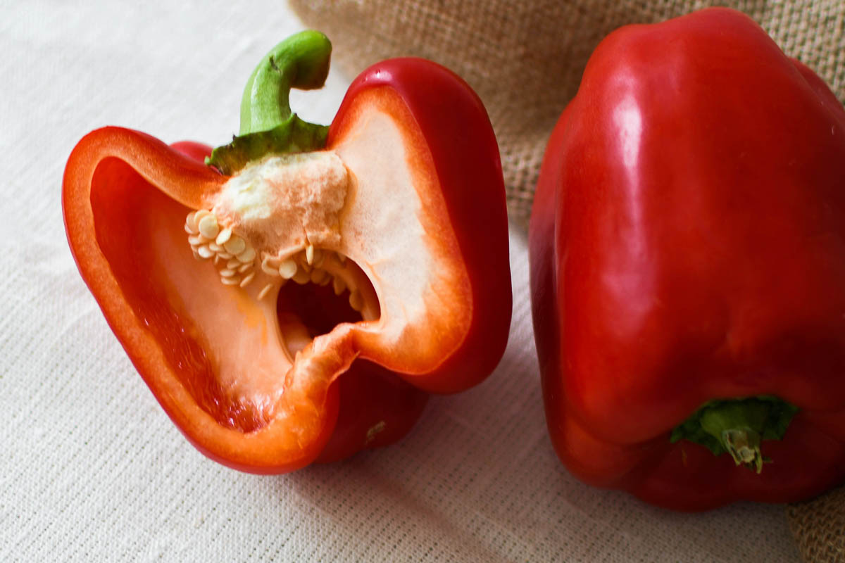 half a red pepper next to a whole red pepper, listed on EWG's Dirty Dozen List.