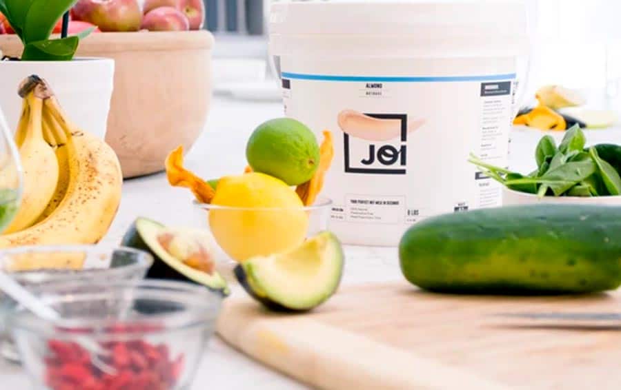 Joi nutbase for quick plant-based milk, surrounded by fresh produce.